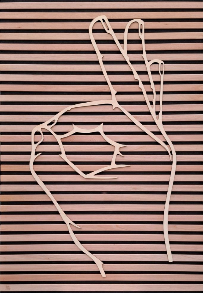 Grote houten hand met de gebarentaal handvorm met de betekenis "PERFECT"
op zwart paneel met houten dwarslatten bevestigd