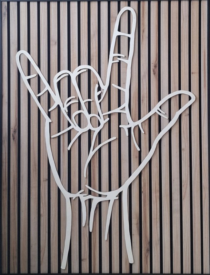 Grote houten hand met de gebarentaal handvorm met de betekenis "ik hou van jou"
op akoestisch paneel bevestigd