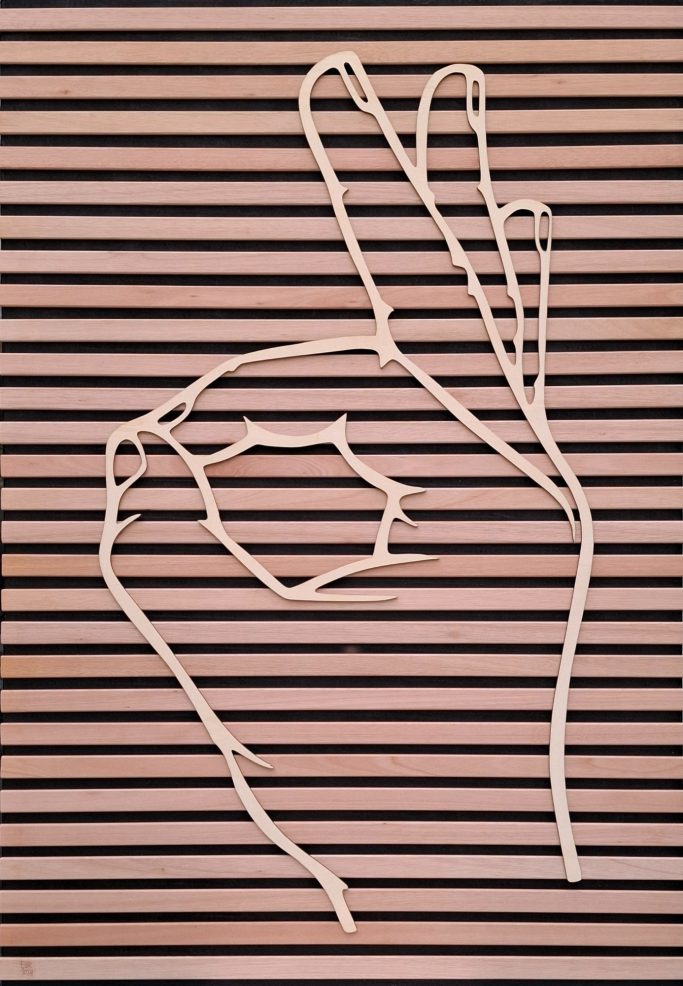 Grote houten hand met de gebarentaal handvorm met de betekenis "PERFECT"
op zwart paneel met houten dwarslatten bevestigd