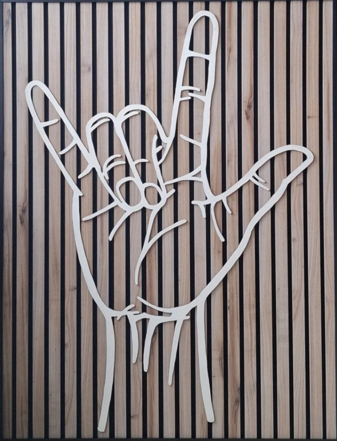 Grote houten hand met de gebarentaal handvorm met de betekenis "ik hou van jou"
op akoestisch paneel bevestigd